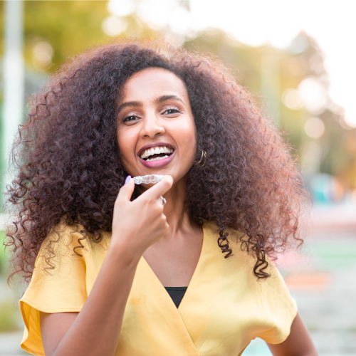 Beautiful smiling African woman is holding Invisalign<br />
