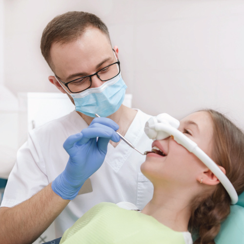 male dentist treats teeth to female patient on dental chair